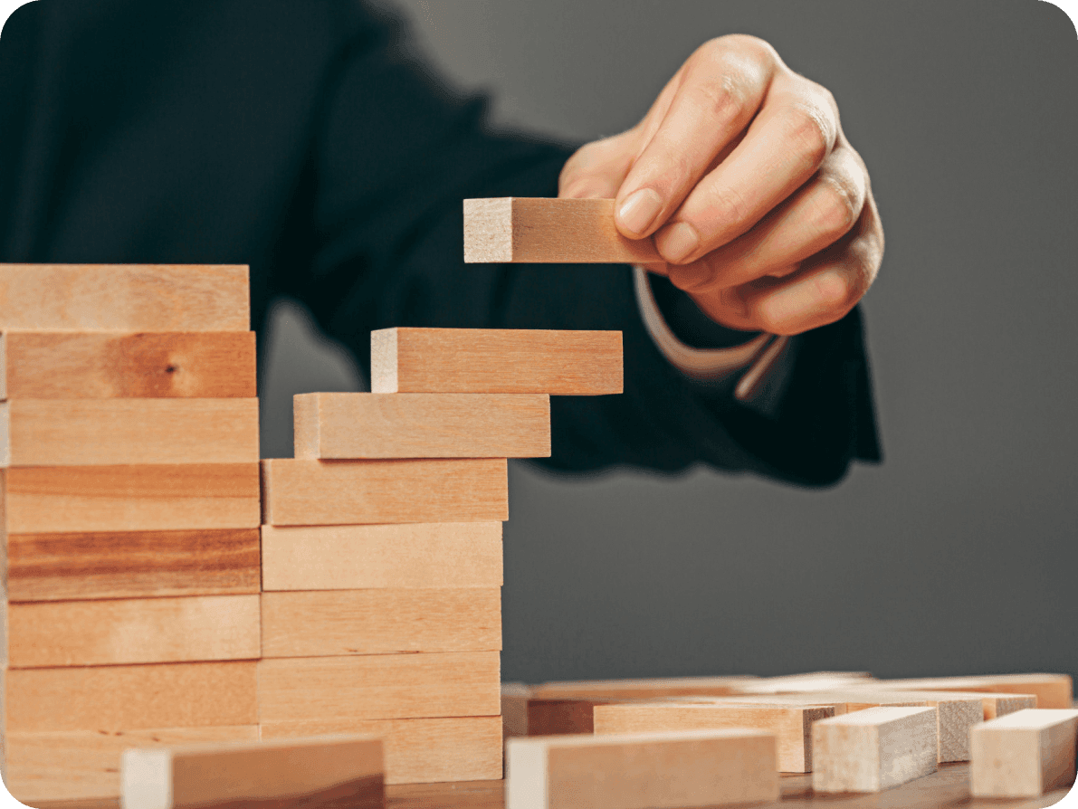 A man in a suit carefully constructs a tower of wooden blocks, symbolizing the concept development phase of a project