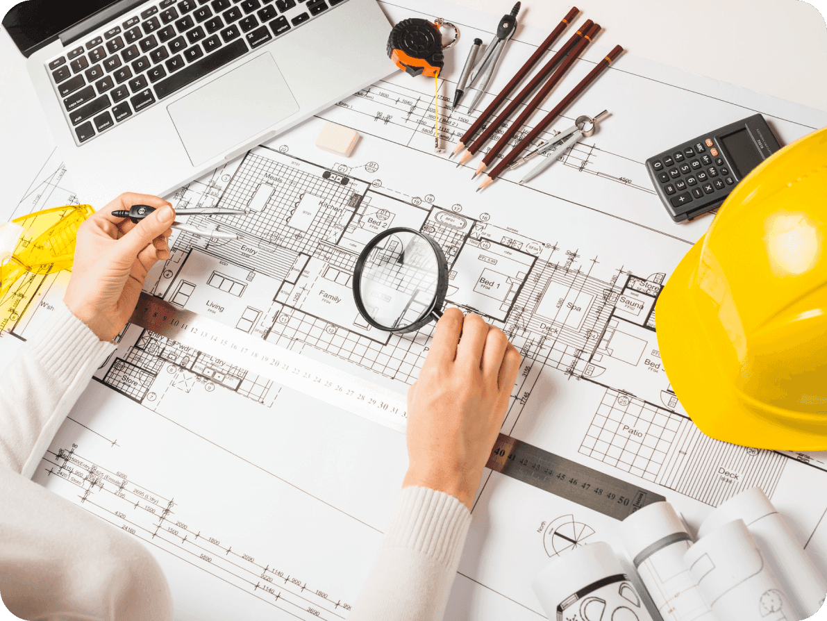 A person examines architectural drawings with a magnifying glass, highlighting attention to detail in engineering design