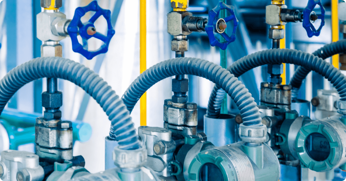 Industrial pipes with blue valve handles and flexible connections are meticulously arranged, showcasing the precision required in gas processing systems